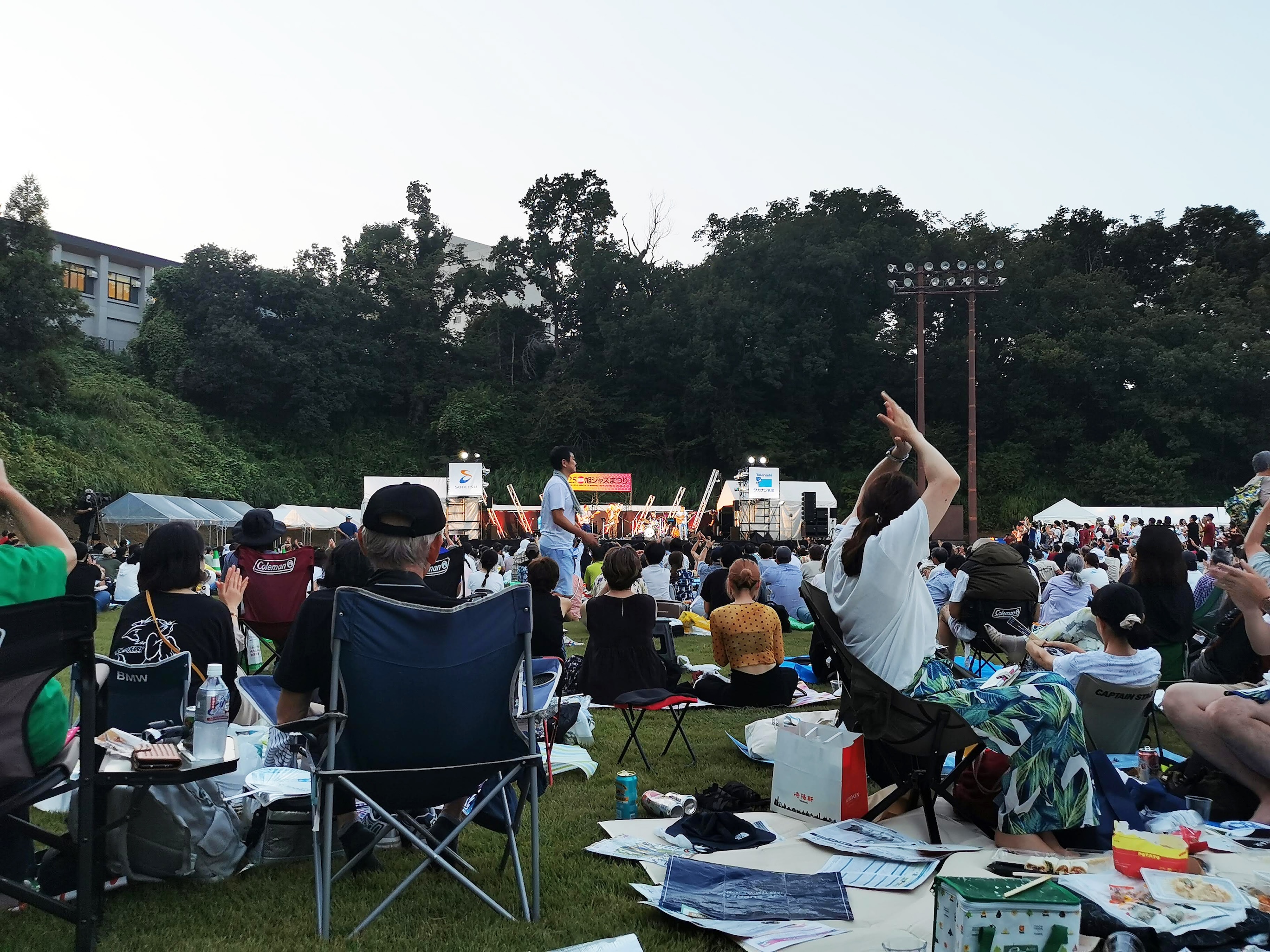 夕暮れの芝生広場で音楽に盛り上がる観客たち